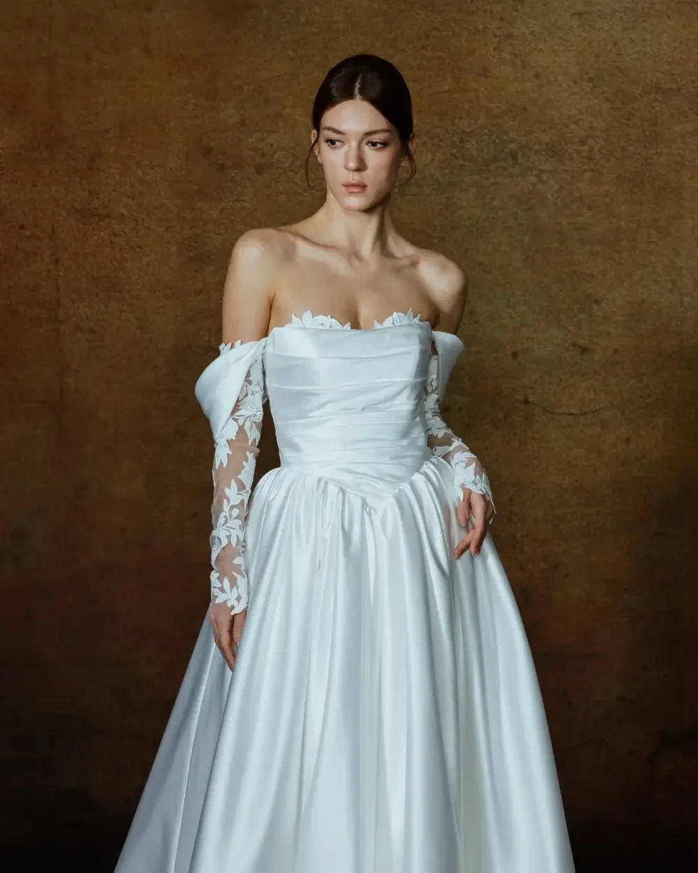 model is wearing an off the shoulder wedding gown